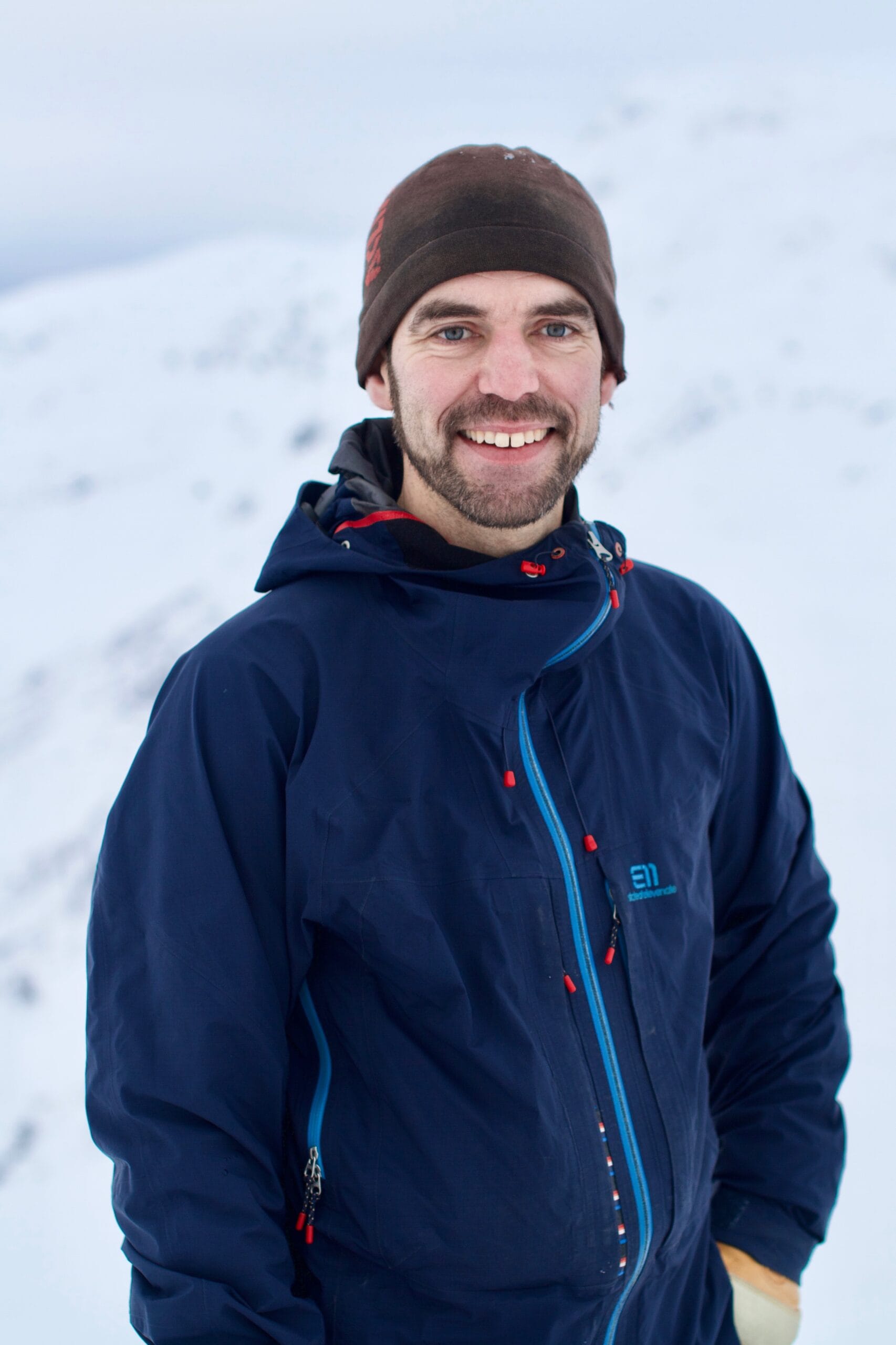 Portrett av guide og medier i Wild Voss Øystein Ormåsen med et hvitt vinterlandskap i bagrunnen. 